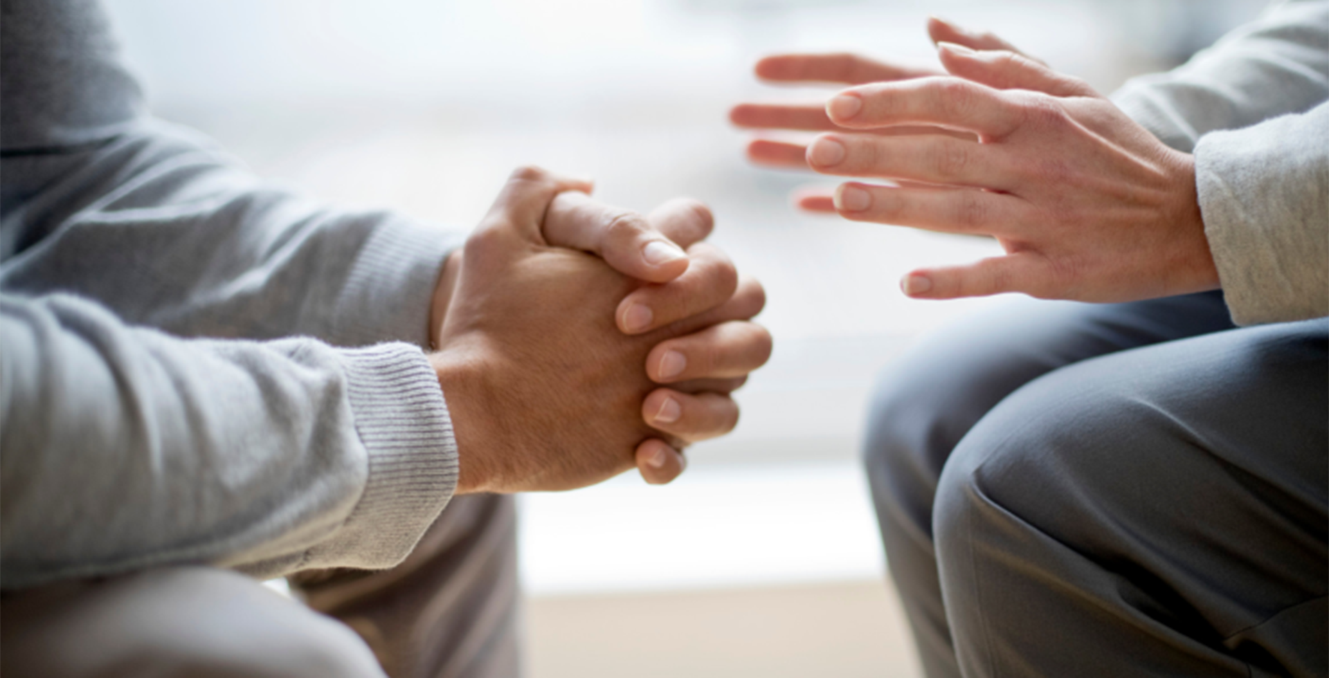 Close up of the hands of two men sitting.
